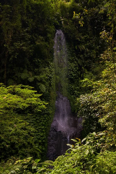 Waterfall landscape. Small hidden waterfall in tropical rainforest. Foreground with big stones. Slow shutter speed, motion photography. Travel and adventure. Bali, Indonesia