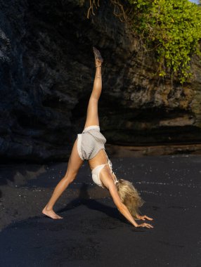 Bali 'de yoga. Genç kadın Eka Pada Adho Mukha Svanasana, Tek Ayaklı İt. Sağlam vücut, düz sırt. Sağlıklı bir yaşam tarzı. Yoga inzivası. Uzayı kopyala Bali 'de plaj