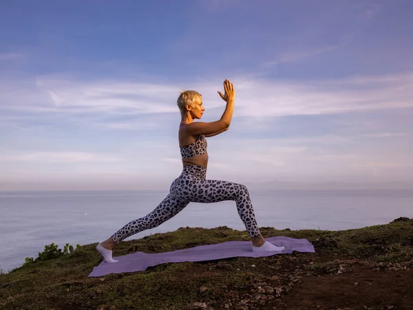 Virabhadrasana I, Savaşçı I Poz veriyor. Eller namaste mudra 'da. Yoga inzivası. Sağlık sigortası konsepti. Denge ve konsantrasyon. Sağlıklı bir yaşam tarzı. Uluwatu uçurumu, Bali, Endonezya