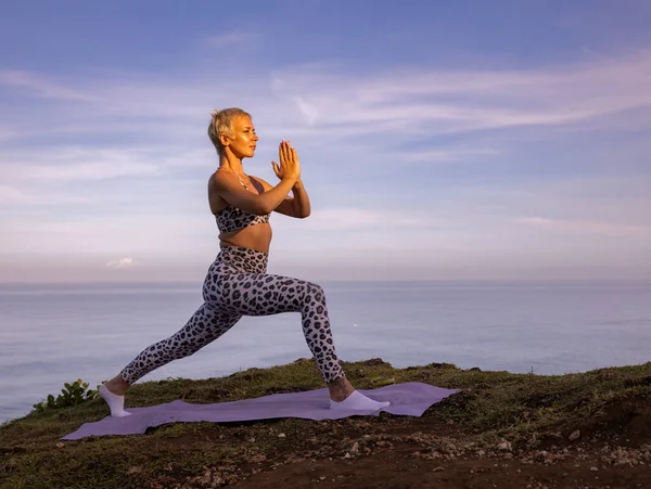 Virabhadrasana I, Savaşçı I Poz veriyor. Eller namaste mudra 'da. Yoga inzivası. Sağlık sigortası konsepti. Denge ve konsantrasyon. Sağlıklı bir yaşam tarzı. Uluwatu uçurumu, Bali, Endonezya