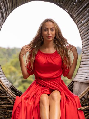 Bali trendi. Tropikal ormanda saman yuvası. Pipet yuvasında fotoğraf çeken uzun kırmızı elbiseli beyaz bir kadın. Asya 'da tatil. Seyahat yaşam tarzı. Yaz kavramı. Bongkasa, Bali, Endonezya