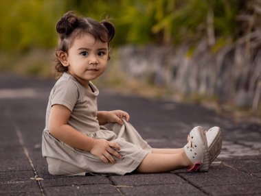 Kumsalın yanındaki gezinti güvertesinde oturan tatlı küçük kız. Sıcak, güneşli bir gün. Yaz tatili. Tatil konsepti. Elbise giyen küçük kız. Pandawa Plajı, Bali, Endonezya