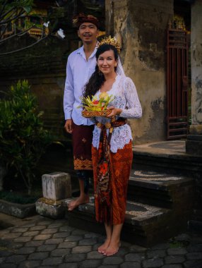 Bali seremonisi için hazırlık. Çok kültürlü bir çift, Hindu dini törenine hazırlanıyor. Tanrı 'nın adaklarıyla. Kültür ve din. Beyaz bir eş ve Balili bir koca. Penglipuran, Bali