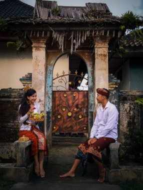 Geleneksel Bali töreni için hazırlık. Çok kültürlü bir çift adak adayarak Hindu dini töreni yapıyor. Kültür ve din. Beyaz bir eş ve Balili bir koca. Penglipuran, Bali