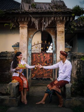 Geleneksel Bali töreni için hazırlık. Çok kültürlü bir çift adak adayarak Hindu dini töreni yapıyor. Kültür ve din. Beyaz bir eş ve Balili bir koca. Penglipuran, Bali