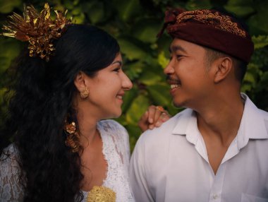 Geleneksel Bali kıyafetleri giyen çok kültürlü bir çiftin portresi. Beyaz bir eş ve Balili bir koca. Mutlu bir çift. Romantik bir ilişki. Bali kültürü. Penglipuran, Bali, Endonezya