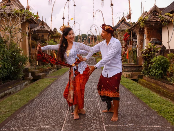 Geleneksel Bali dansı yapan çok kültürlü bir çift. Penjor bambu süslemesi. Beyaz bir eş ve Balili bir koca. Romantik bir ilişki. Penglipuran, Bali, Endonezya
