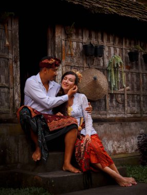 Mutlu, çok kültürlü bir çift. Romantik bir kavram. Birbirine aşık bir çift. Bambu evi. Beyaz kadın ve Balili koca geleneksel kıyafetler giyiyor. Penglipuran köyü, Bali, Endonezya