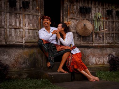 Mutlu, çok kültürlü bir çift. Romantik bir kavram. Birbirine aşık bir çift. Bambu evi. Beyaz kadın ve Balili koca geleneksel kıyafetler giyiyor. Penglipuran köyü, Bali, Endonezya