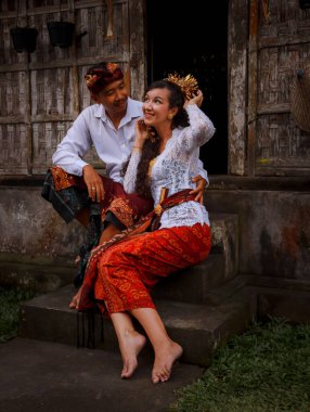 Mutlu, çok kültürlü bir çift. Romantik bir kavram. Birbirine aşık bir çift. Bambu evi. Beyaz kadın ve Balili koca geleneksel kıyafetler giyiyor. Penglipuran köyü, Bali, Endonezya
