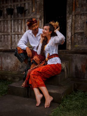 Mutlu, çok kültürlü bir çift. Romantik bir kavram. Birbirine aşık bir çift. Bambu evi. Beyaz kadın ve Balili koca geleneksel kıyafetler giyiyor. Penglipuran köyü, Bali, Endonezya