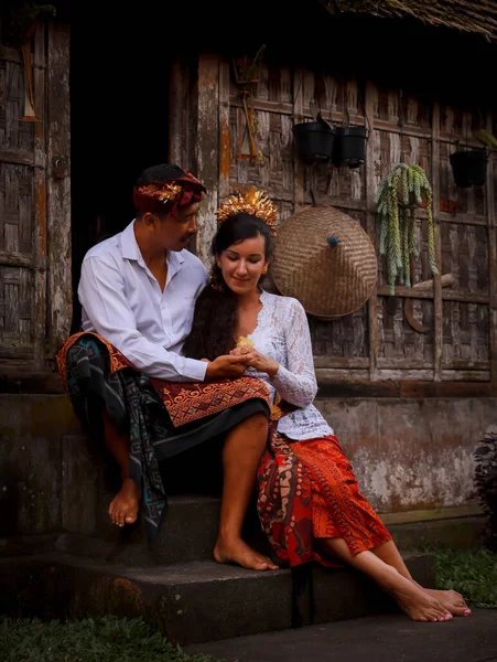 Mutlu, çok kültürlü bir çift. Romantik bir kavram. Birbirine aşık bir çift. Bambu evi. Beyaz kadın ve Balili koca geleneksel kıyafetler giyiyor. Penglipuran köyü, Bali, Endonezya