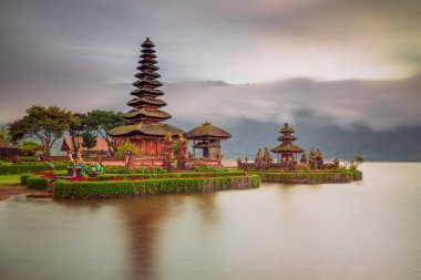 Bali adasındaki Pura Ulun Danu Bratan tapınağı. Güneş doğarken çok güzel bir bale tapınağı. Bali 'nin simgesi. Bulutlu gökyüzü. Su yansıması. Kapama hızı yavaş. Bratan Gölü, Bali, Endonezya