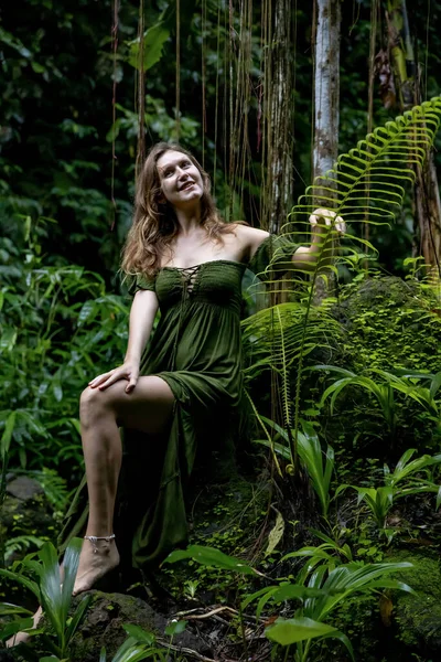 Жінка Джунглях Сидить Камені Оточеному Буйними Зеленими Рослинами Торкаючись Листя — стокове фото