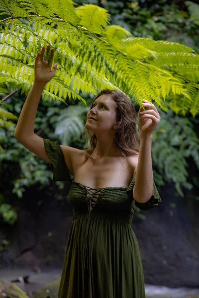 シダの葉の下に美しい女性の肖像画 熱帯ジャングルを歩く緑のドレスを着た白人女性 自然と環境の概念 アジアへの旅行 インドネシアのバリ島 — ストック写真