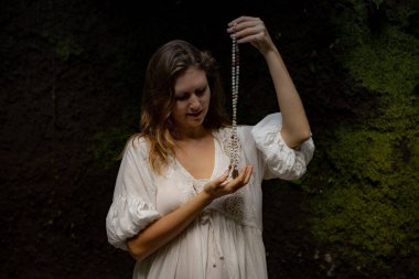 Beyaz kadın dua ve meditasyon için Mala 'yı tutuyor. Budist japa mala doğal taşlardan yapılmış. Din kavramı. Budist mücevherleri. Beyaz elbiseli bir kadın. Bali, Endonezya