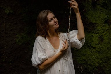 Beyaz kadın dua ve meditasyon için Mala 'yı tutuyor. Budist japa mala doğal taşlardan yapılmış. Din kavramı. Budist mücevherleri. Beyaz elbiseli bir kadın. Bali, Endonezya