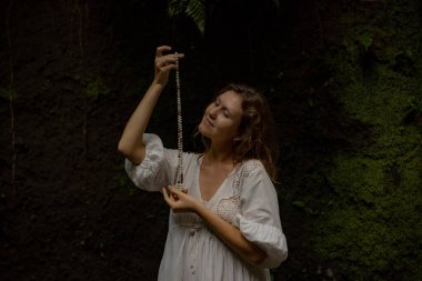 Beyaz kadın dua ve meditasyon için Mala 'yı tutuyor. Budist japa mala doğal taşlardan yapılmış. Din kavramı. Budist mücevherleri. Beyaz elbiseli bir kadın. Bali, Endonezya