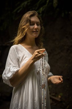 Kafkasyalı kadın dua ve meditasyon sırasında saymaya devam ediyor. Gyan Mudra 'yı teslim edin. Budist japa malası. Değerli boncuk iplikleri. Din kavramı. Budist mücevherleri. Beyaz elbiseli bir kadın. Bali