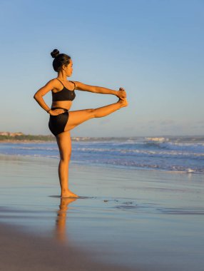 Sahilde yoga antrenmanı. Utthita Hasta Padangusthasana, Uzatılmış Elden Büyük Parmağa Poz. Asana 'yı dengeliyorum. Vücuda uygun. Sağlıklı bir yaşam tarzı. Bağışıklık sistemini destekleyin. Uzayı kopyala Seminyak plajı, Bali