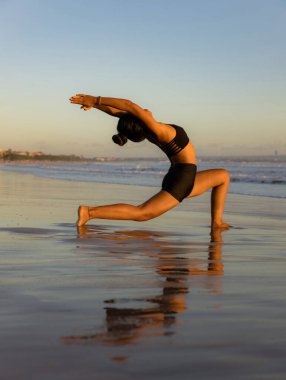 Sunset plaj yogası. Anjaneyasana, Low Lunge Poz. Hilal Ay Pozu. Asana 'yı bükerek geri hamle yapmak. Kas destekleyici. Esnek omurga ve sırt. Sağlıklı bir yaşam tarzı. Uzayı kopyala Seminyak plajı, Bali