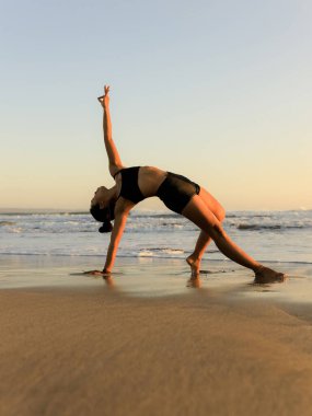 Gün batımında plajda yoga antrenmanı. Güzel Asana. İnce vücut. Sağlıklı bir yaşam tarzı. Yoga inzivası. Uzayı kopyala Seminyak Sahili, Bali, Endonezya