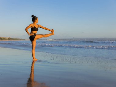 Sahilde yoga antrenmanı. Utthita Hasta Padangusthasana, Uzatılmış Elden Büyük Parmağa Poz. Asana 'yı dengeliyorum. Mükemmel bir vücut. Sağlıklı bir yaşam tarzı. Yoga inzivası. Uzayı kopyala Seminyak plajı, Bali
