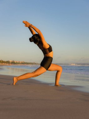 Plaj yogası Ashta chandrasana. Yüksek atlama pozu vücudun kenarlarını uzatır, kalçaları açar. Eller namaste mudra 'da. Sağlıklı bir yaşam tarzı. Yoga inzivası. Vücuda uygun. Seminyak Sahili, Bali, Endonezya