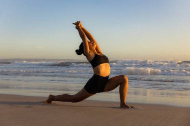 Sunset plaj yogası. Anjaneyasana, Low Lunge Poz. Hilal Ay Pozu. Asana 'yı bükerek geri hamle yapmak. Kas destekleyici. Esnek omurga ve sırt. Yoga inzivası. Uzayı kopyala Seminyak Sahili, Bali, Endonezya
