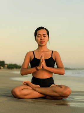 Yoga inzivası. Lotus pozu veren Asyalı kadın. Padmasana. Eller namaste mudra 'da. Kapalı gözler. Sağlıklı bir yaşam tarzı. Sahilde yoga. Uzayı kopyala Seminyak Sahili, Bali, Endonezya