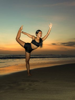 Sunset plaj yogası. İnce kadın yoga yapıyor, Natarajasana 'da duruyor, Dans Pozu Lordu. Dengede duruyor, Asana 'yı büküyor. Kumsalda egzersiz. Uzayı kopyala Seminyak Sahili, Bali, Endonezya