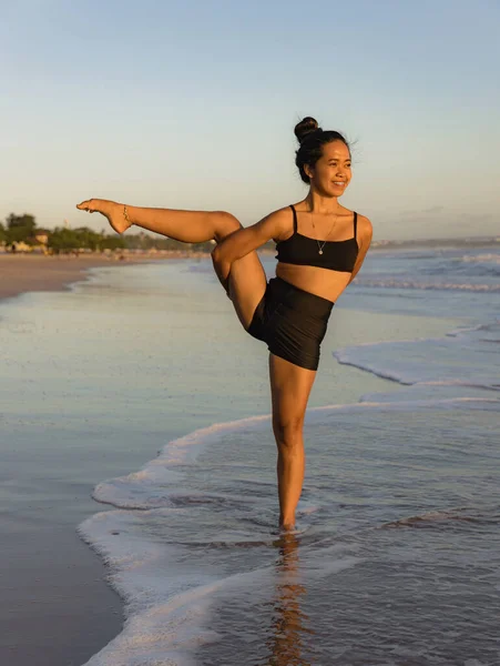 Sahil yogası. Svarga Dvijasana, Cennet Kuşu Pozu. Güçlü bacaklar. Asana 'yı dengeliyorum. Sağlıklı bir yaşam tarzı. Mükemmel bir vücut. Uzayı kopyala Yoga inzivası. Seminyak plajı, Bali Endonezya