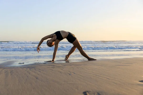 Yoga inzivası. Güzel Asana. İnce kadın sahilde yoga yapıyor. Esneme egzersizi. Esnek vücut. Uzayı kopyala Yatay yerleşim planı. Seminyak Sahili, Bali, Endonezya