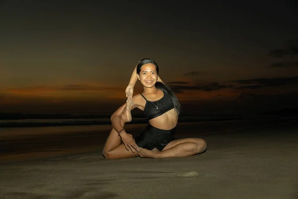 Sunset beach yoga. Woman practicing Eka Pada Rajakapotasana, One Legged King Pigeon Pose. Chest opener improving breathing. Self care concept. Yoga retreat. Copy space. Seminyak beach, Bali