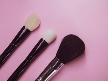 Pembe arka planda üç makyaj fırçası. Maskara ve pudra için profesyonel fırçalar. Makyaj
