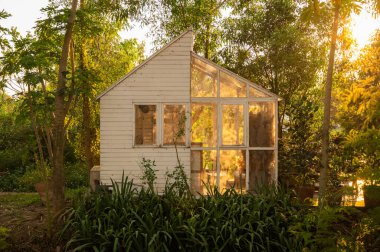Bahçedeki hafif ve havadar döşenmiş güneş odası (konservatuar), akşamleyin güneş ışığına sahiptir. İngiliz ülke tarzı.