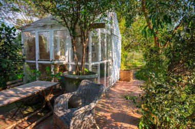 Öğleden sonra bahçedeki hafif ve havadar döşenmiş güneş odası (konservatuar) güneş ışığına sahiptir. İngiliz kır tarzı. Oturma alanı dinlenmek ve doğanın tadını çıkarmak için.