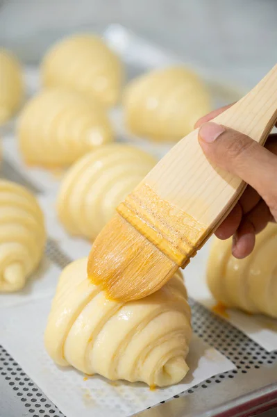 Preparación Croissants Para Hornear Cepillado Con Huevo Imagen de stock