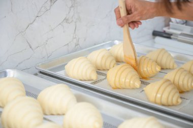 Çiğ kruvasan tepside yumurta fırçalamaya hazır..