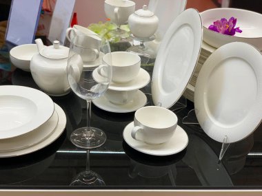 Siyah masadaki beyaz tabaklar. Şarap kadehi ve çorba kaseleri. Yeni yemeklerin sunumu.