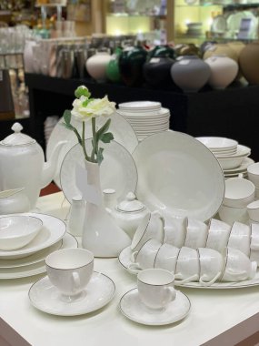 Çay seremonisi için beyaz çatal bıçaklar. Seramik beyaz vazo masanın üzerinde duruyor. Masa ayarı, seramik yemekler..