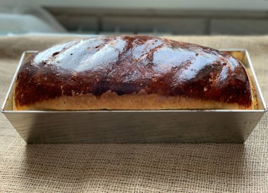 Fırın kabında bir somun ekmek. Pencereden gün ışığı. Ev yapımı ekmek. Fırın ürünü kapanıyor..