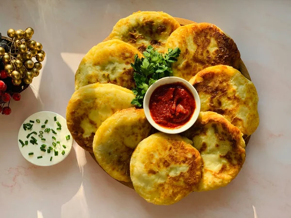 Traditional potato tortillas on the table. Zrazy with meat and tomato sauce in a saucepan. Homemade flatbreads for dinner.