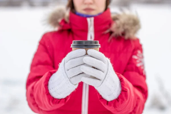 冬天穿着红色夹克的年轻女人拿着一杯热咖啡或茶 一个大雪的冬天 一杯热饮来保暖 冬天喝一杯咖啡 — 图库照片