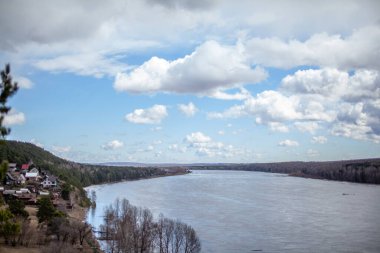 Ormanlar ve kayalık kıyılar arasında güzel, geniş bir sonbahar nehri. Sonbahar renkleriyle sakin ve sessiz bir yer. Bulutların güzel havadaki yansıması.