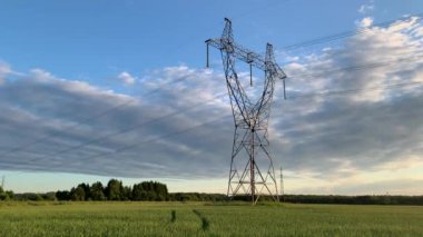 Metal kutuplar yazın tarlalardaki yüksek voltajlı kablolar için elektrik destekleri. Yüksek voltaj kutupları veya elektrik kulesi yeşil alan enerji teknolojisi kavramında yüksek voltajlı iletim yeridir.