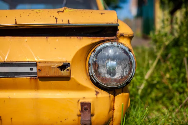 Antiguo coche destrozado amarillo en estilo vintage. coche amarillo oxidado abandonado. — Foto de Stock