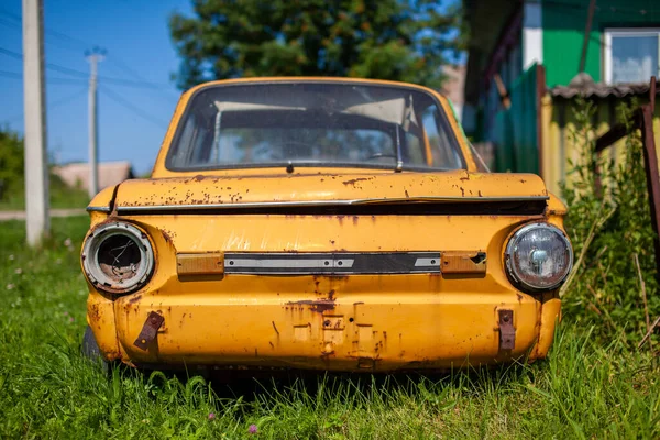 Old yellow wrecked car in vintage style. Abandoned rusty yellow car.
