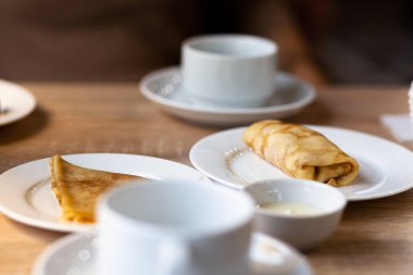 Kahve için beyaz bardakların yanındaki masaya doldurulmuş taze krepler ya da kahvaltıda çay. Yemekten sonra sıcak bir kahveye tatlı olarak krep..