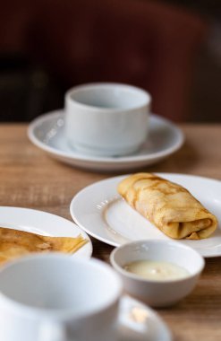 Kahve için beyaz bardakların yanındaki masaya doldurulmuş taze krepler ya da kahvaltıda çay. Yemekten sonra sıcak bir kahveye tatlı olarak krep..